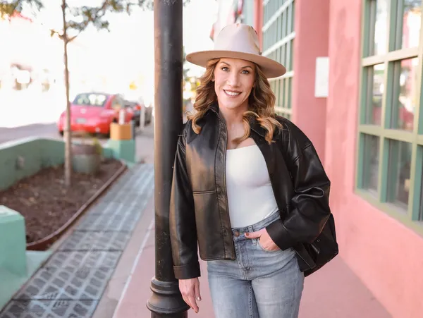 Portrait of Laurie outdoors in hat, leaning on lamppost